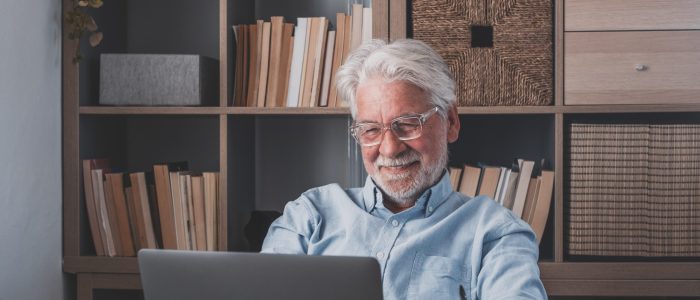 Happy old caucasian businessman smiling working online watching