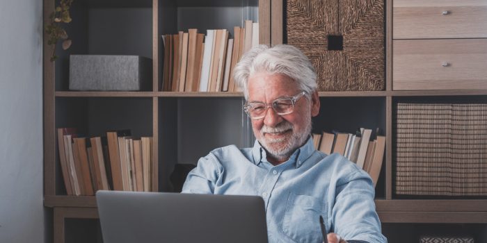 Happy old caucasian businessman smiling working online watching