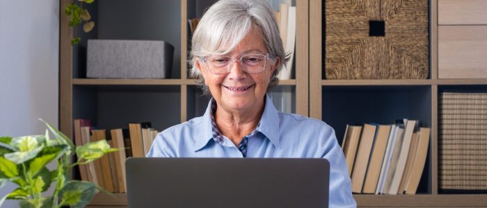 Happy old caucasian businesswoman smiling working online watchin